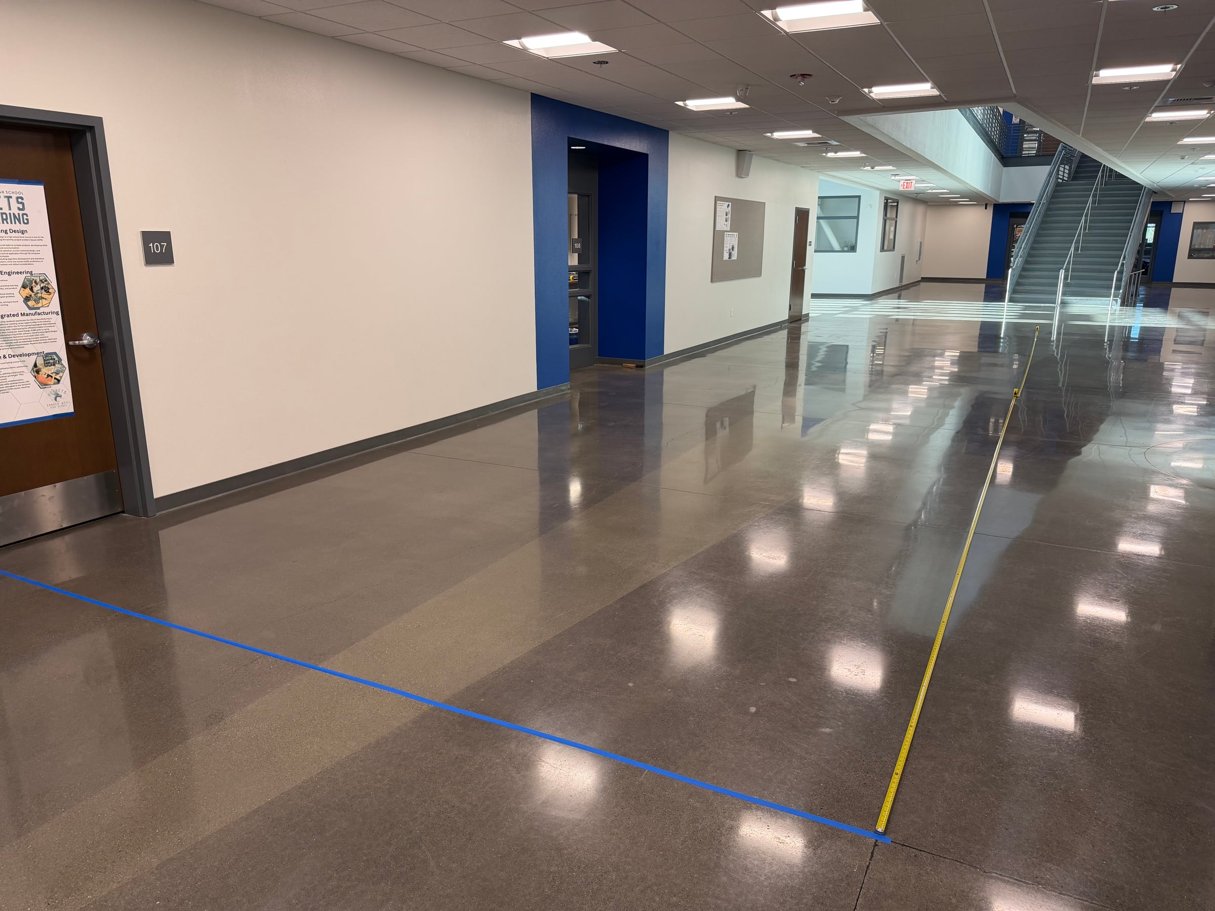 Paper-airplane testing hallway with a blue starting line and tape measures