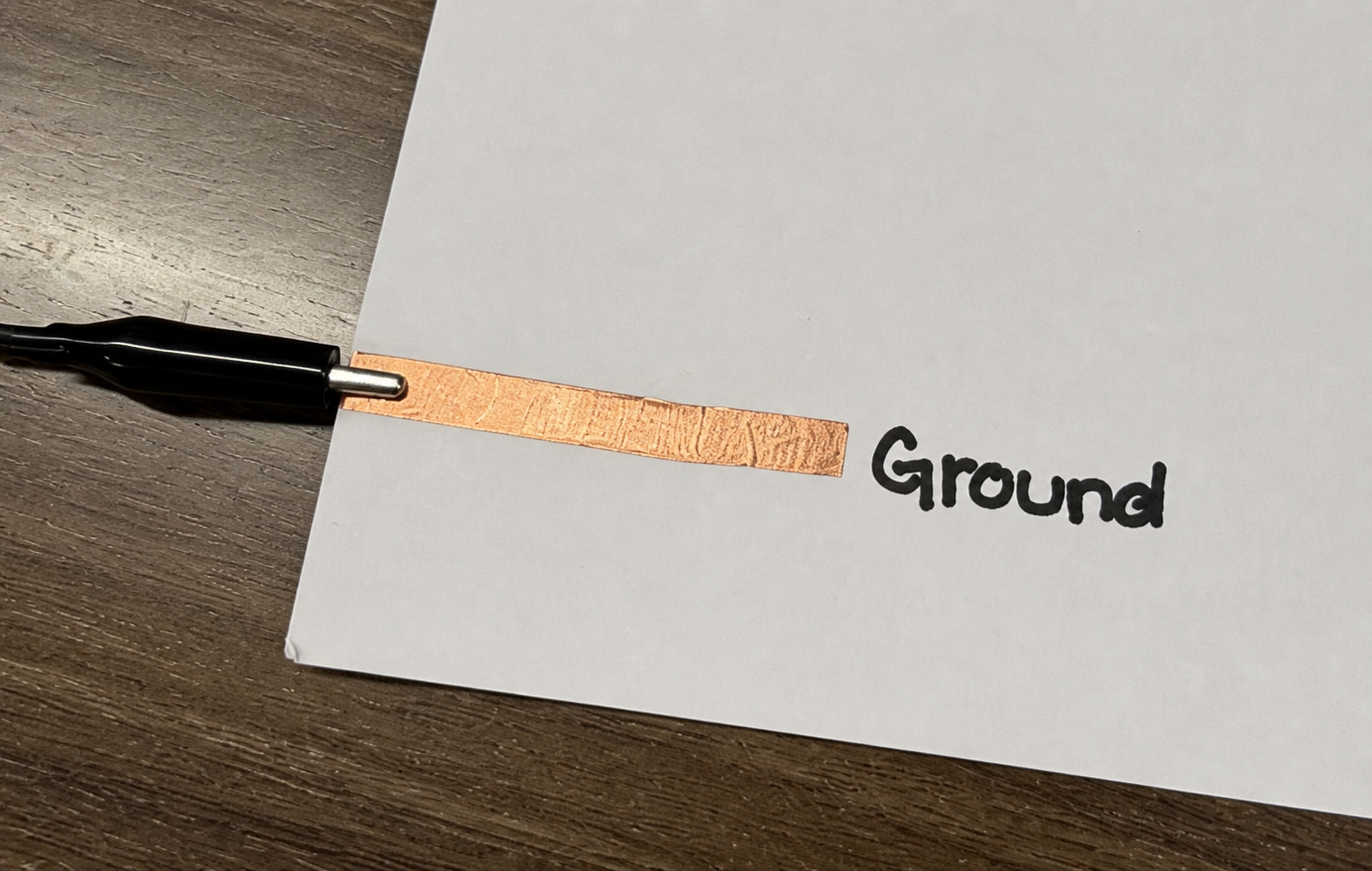 Close view of the paper piano's copper-tape ground key and black alligator clip
