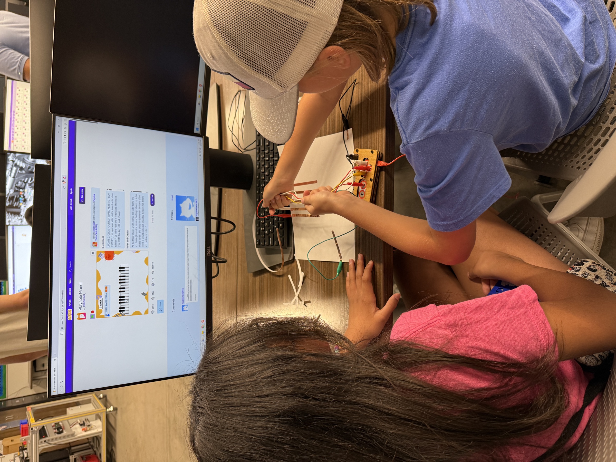 Students tracing alligator clips between copper-tape controls and a Makey Makey