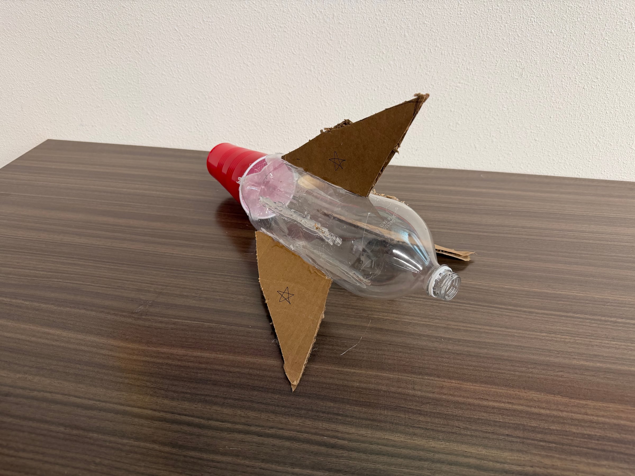 Instructor-built bottle rocket with cardboard fins and a red plastic cup nose