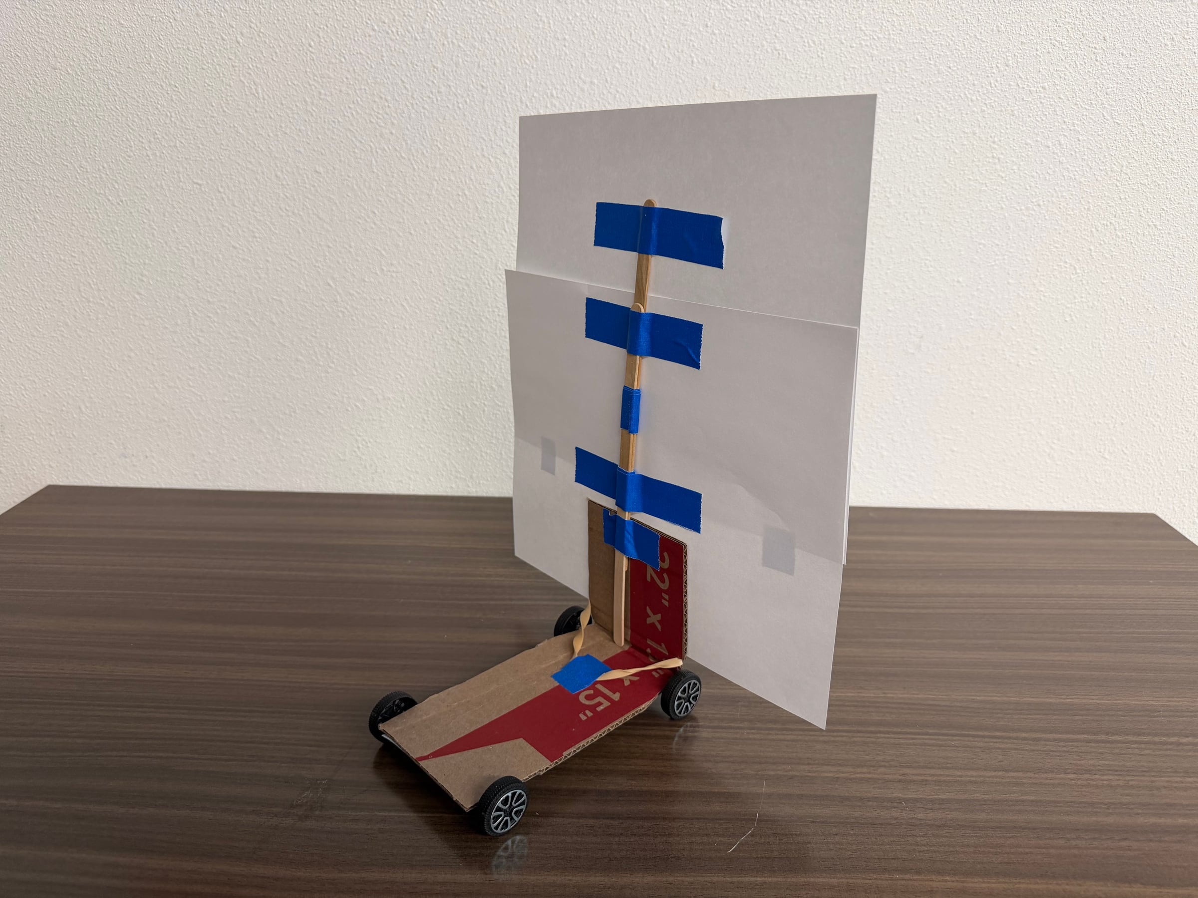 Instructor-built wind-powered car with a tall paper sail